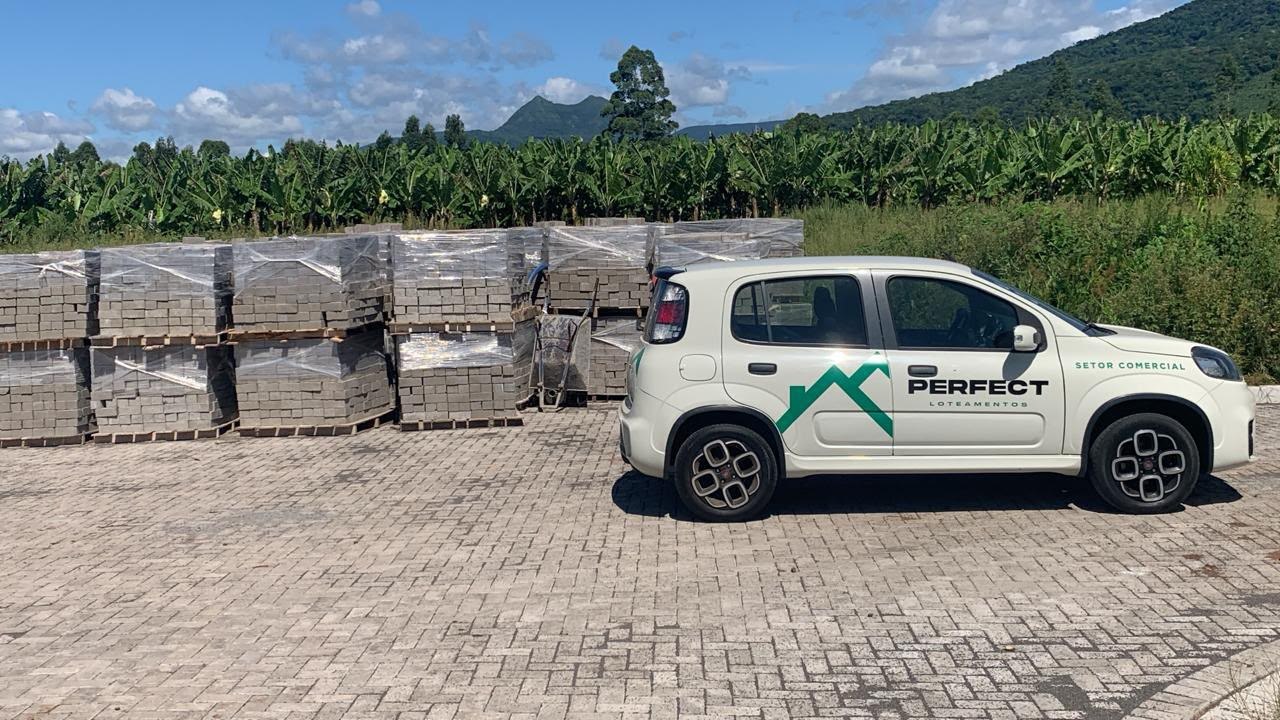 Veículo da Perfect Loteamentos ao lado de paletes de pavers em obra